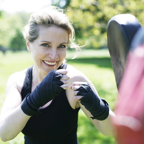 Senior woman with personal fitness trainer doing sport on meadow